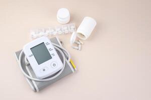 Digital blood pressure tonometer and pack of pills on the light background with copy space. photo