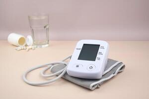 The Digital blood pressure tonometer and pack of pills on a light background. photo