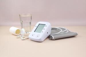 The Digital blood pressure tonometer and pack of pills on a light background with copy space. photo