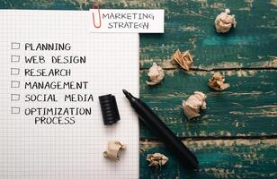 Black marker sits on a piece of paper with a list of marketing strategies photo