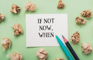 Piece of paper with the words if not now, when written on it photo