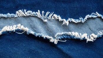 torn denim fabric with frayed edges, macro close-up of ripped blue jeans showing inner thread texture for textile or fashion background photo