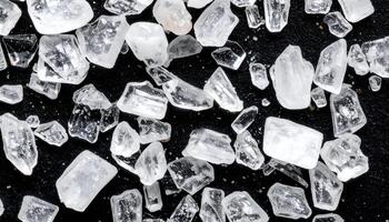 extreme macro close-up of sea salt crystals on black surface, transparent mineral seasoning grains with sharp angles and natural sparkle texture photo
