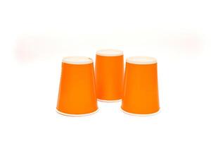 Three vibrant orange cups with white lids arranged on a clean white surface, creating an inviting and playful composition photo