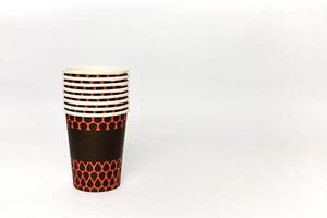 Stack of disposable paper cups with a brown and orange pattern against a white background photo