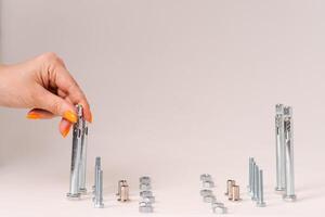 screws and nuts and bolts, stand on a light background, the hand moves the bolt construction concept photo