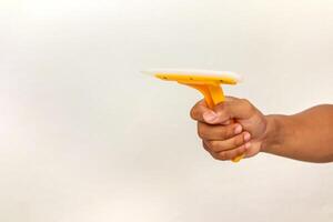 Close-up of a hand holding a yellow window squeegee against a white background ready to clean the glass photo