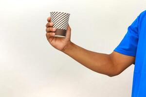 Hand holding a paper cup with diagonal stripes against a white background isolated photo