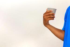 Hand holding striped cup against a plain background in a simple composition photo