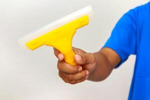 Hand Holding a Yellow Squeegee for Window Cleaning or Surface Wiping Tasks photo