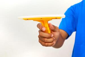 A close-up shot of a hand holding a yellow and white squeegee on a white background photo