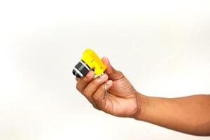 A person's hand holding a yellow macro lens attachment for a mobile phone camera with a white background, studio photography photo