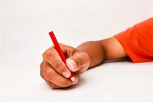Close up of a hand holding a red pencil against a white background ready to write or draw photo