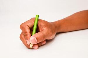 Close-up of hand holding a green pencil poised to write on a white surface for creative projects photo