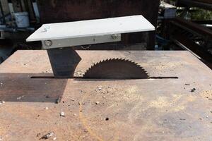 Circular saw blade cutting through wood on rusty table in workshop photo