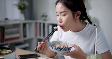 Handheld shot, Asian woman is happy to have delicious noodles for lunch on the table at home. Enjoying hot pot noodles. video