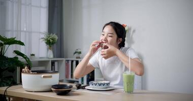 Handheld shot, Asian woman is happy to have delicious noodles for lunch on the table in living room. Enjoying hot pot noodles. video