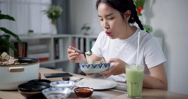 Handheld shot, Happy Asian woman is happy to have delicious noodles for lunch on the table at home. Enjoying hot pot noodles. video