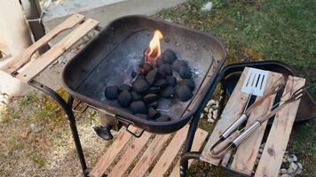 Glowing charcoal briquettes burning intensely with bright orange red flames, creating heat for outdoor summer meal preparation in backyard setting. Burning coal briquettes. Barbecue cooking concept video