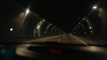 Inside view of highway tunnel driving with slow motion capturing passing vehicles, illuminated signs, and dynamic road perspective from inside moving automobile. Driving through highway tunnel. 4k video