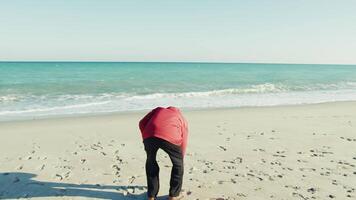 Elderly Man Picks Up Stones on the Sand and Throws Them into the Sea video