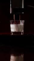 Making coffee into glass cup, espresso coming out from an automatic coffee maker machine. Cappuccino, latte for breakfast in modern dark kitchen. Highlighting process of making aromatic. Vertical shot video