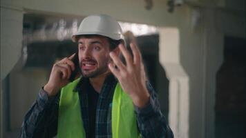 irritado Bravo caucasiano homem construtor capataz discutindo Falando Móvel telefone dentro construção contratante masculino técnico gritando Smartphone engenheiro arquiteto cara desacordo problema conflito construção video
