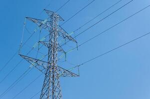 A transmission tower against blue sky. Transmission towers or electrical pylons carry large amounts of high-voltage current over long distances. photo