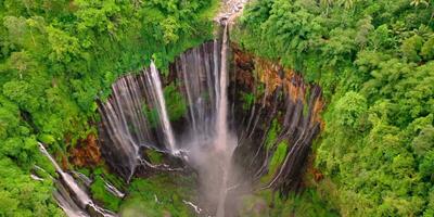 An aerial view of a waterfall in the middle of a lush green forest video