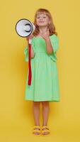 Young blonde child girl kid talking with megaphone, proclaiming news, loudly announcing advertisement, warning using loudspeaker to shout speech. Little preteen children on yellow background. Vertical video