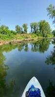 A kayak is floating down a river with trees and grass video