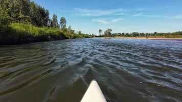 A kayak paddling down a river with trees and grass video