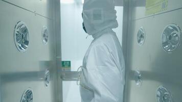 Lab scientist expert in white protection suit walking through the air blowing sanitizing machine to disinfect before working inside the lab, disinfection procedures before entering the laboratory video