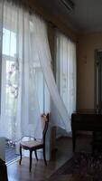 a transparent curtain in a room flutters in the wind from an open door to the balcony video