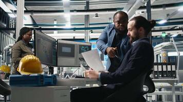 Multiethnic team of energy consultants review insight in solar panel plant, ensuring high standards in alternative energy production line. Quality control and manufacturing process. Camera B. video