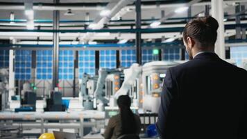 Professional engineer managing the production line for solar panels, examining equipment and efficiency in the modern factory. Businessman expert works on alternative energy. Camera B. video