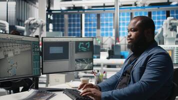 African american master engineer reviews operations in a solar tech plant, ensuring factory activity to meet green energy targets. Specialist uses tablet for manufacturing efficiency. Camera B. video