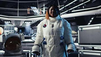 Upbeat astronaut greeting researchers during videocall presenting research data gathered during flight. Friendly woman in space station provides experiments observations to Earth team, camera A video