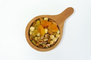 Healthy mix of nuts and dried fruits in wooden spoon on white surface photo