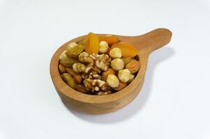 Mix of healthy dried fruits and nuts in a wooden bowl for a healthy snack on a white background, top view angle photo