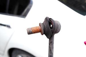 Stabilizer bar link worn out or stabilizer ball joint degraded, A close-up of a rusty, worn anti-roll bar link photo