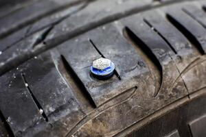 Flat Tire, A close-up of a car tire with a screw or nail embedded in the tread, indicating a puncture and the need for tire repair. photo