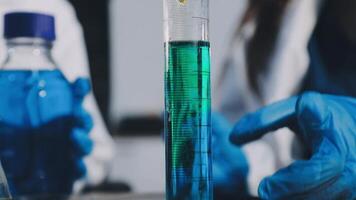A person in blue gloves holding a test tube with a green liquid video