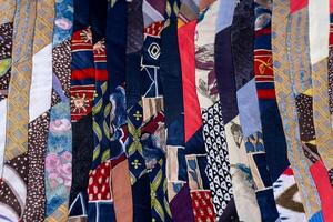 Patchwork Quilt Made of Repurposed Neckties. A fragment of multi-colored pieces of fabric sewn together. photo
