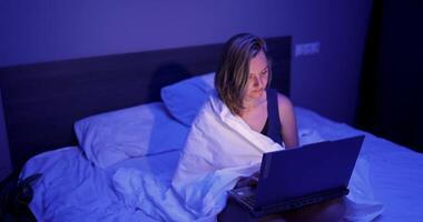 Working late at night while wrapped in a blanket in a cozy bedroom video