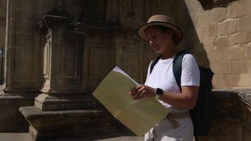 A happy woman tourist explores an old medieval city. Using her map, she joyfully discovers historic architecture and charming streets, fully embracing the spirit of travel and new destinations. video
