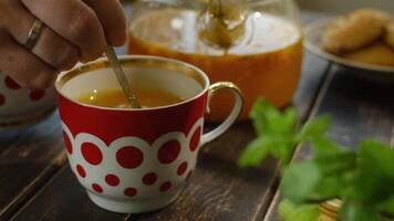 Tea party. Hand stirs sugar in mug of sea buckthorn tea with spoon video