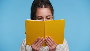Smiling student holding yellow notebook on blue background video