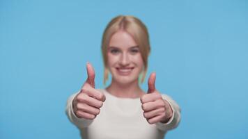 Smiling woman showing double thumbs up gesture on blue background video