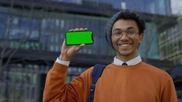 Smiling man nodding in approval while showing smartphone video